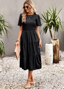 Detail of a black midi dress with a smocked bodice and tiered ruffled hemline