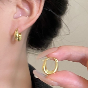 18K gold plated U-shaped geometric hoop earrings with polished finish on model and hand