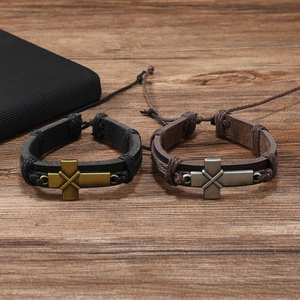 Detail of vintage braided leather bracelets with bronze and silver cross charms