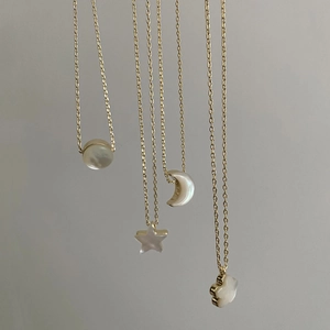Detailed view of gold chain necklaces with natural mother-of-pearl star and moon charms