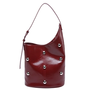 Deep red patent leather bucket bag with silver rivet studs and a long shoulder strap