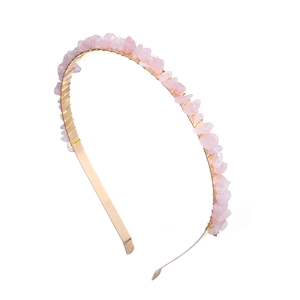 Macro shot of handmade gold wire wrapping around pink natural stones on a hairband