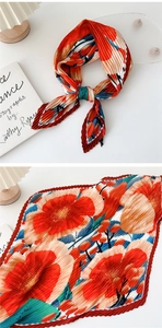 Detail of pleated silk scarf with bright orange floral patterns and accordion texture