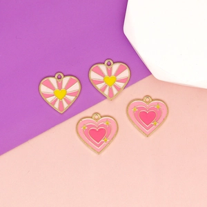 Macro detail of pink heart enamel charms with gold frames and star patterns for DIY jewelry