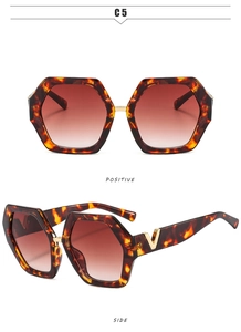 Macro view of oversized hexagonal sunglasses with amber frames and gold V temple detail