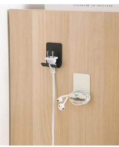 Adhesive wall-mounted plug holders in black and beige for cable management