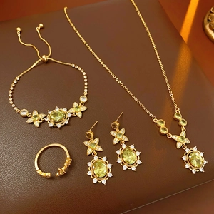 Détail d'un ensemble collier, bracelet et boucles d'oreilles dorés avec zircons verts