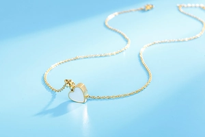 Gros plan d'un collier pendentif coeur doré avec nacre sur un fond bleu clair épuré