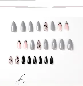 Detail of almond press-on nails featuring grey, black, and silver polka dot patterns