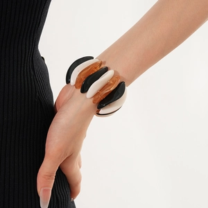 Detail of chunky resin stretch bracelet in black, white, and amber wave shapes