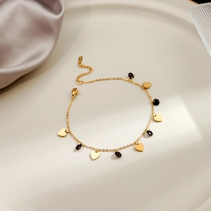 Detail of gold heart charms and black gemstone accents on a sleek geometric bracelet