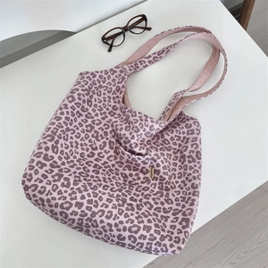 Detail view of pink leopard print suede tote bag with front pocket and woven label