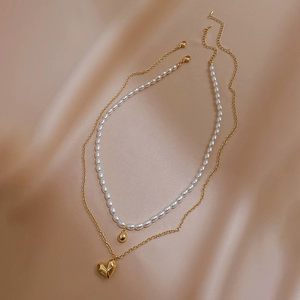 Double-layer gold heart and pearl necklace set on elegant champagne silk background