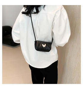 Vue détaillée d'un sac d'épaule en cuir noir avec fermoir papillon en métal blanc
