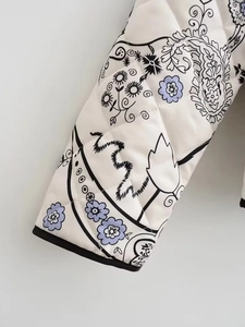 Detailed macro view of quilted jacket cuff with floral paisley print and black piping