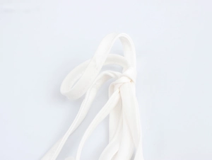 Close-up detail of white fabric shoulder straps tied in a knot on a cropped floral top