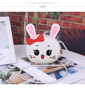 Detail of white rabbit crossbody bag with red bow and silver woven shoulder strap