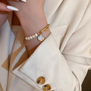 Elegant freshwater pearl bracelet with number five pendant worn on a model's wrist