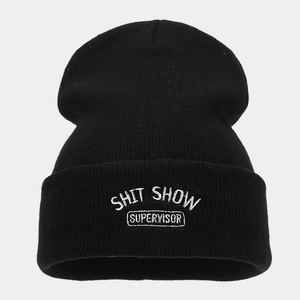 Dettaglio del ricamo bianco SHIT SHOW SUPERVISOR sul berretto in maglia nero