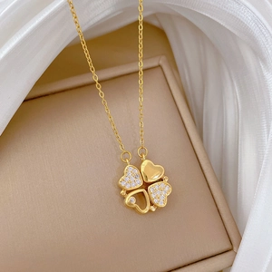 Detailed view of gold clover necklace featuring pave-set crystals and heart motifs