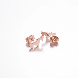 Close-up of rose gold earrings featuring a triple heart design with polished finish