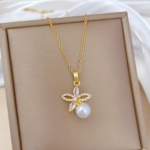 Macro detail of gold flower pendant with sparkling zircons and a white pearl on silk