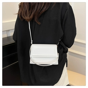 Detailed view of a white leather flap handbag worn as a shoulder bag by a model