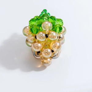 Detail of a handmade champagne glass grape charm with green leaf bead and multifaceted design