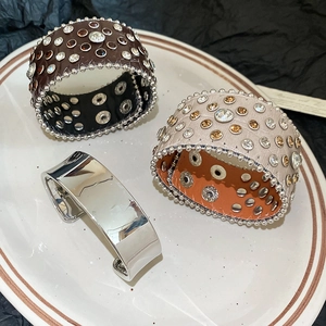 Gros plan de bracelets en cuir à strass et bracelet argenté sur une assiette en céramique