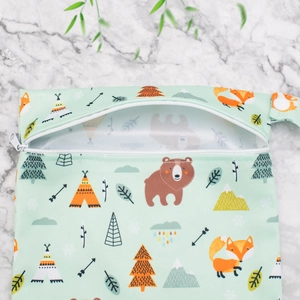 Flat lay of a mint green waterproof wet bag with forest animal prints and zipper closure