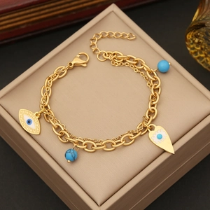 Golden double-layered evil eye bracelet with turquoise beads and lobster clasp on jewelry box