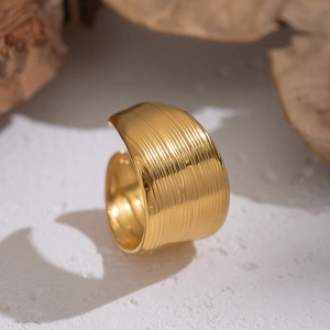 Brushed gold stainless steel wide band open ring on a natural stone surface