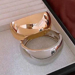 Polished gold and silver wide open cuffs displayed on a luxury jewelry tray