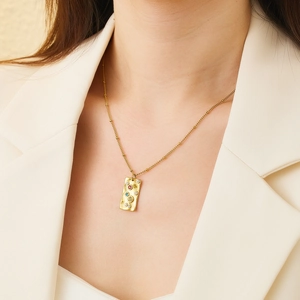 Detail of 18k gold plated titanium necklace with colorful stones and hammered texture