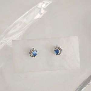 Macro detail of star and moon stud earrings with blue cat eye stone and micro-set zircons