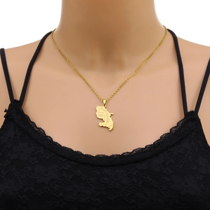 Detail of a gold Martinique map pendant necklace worn over black lace fabric