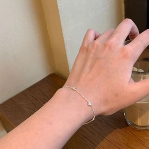 Detailed view of a delicate S925 sterling silver chain bracelet with small heart charms