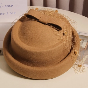 Detail of wool beret featuring a brown mesh bow and delicate gold polka dots