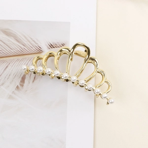 Detailed close-up of crown-shaped golden hair claw clip with elegant pearls