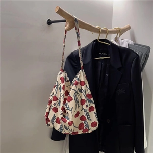 Detail of floral cotton tote bag with red poppy patterns hanging on a wooden hook