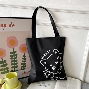Close-up of black Oxford tote bag with white cat art print and decorative background
