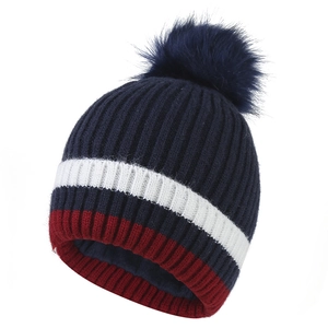 Dettaglio del berretto in maglia blu scuro con strisce bianche e rosse e pompon