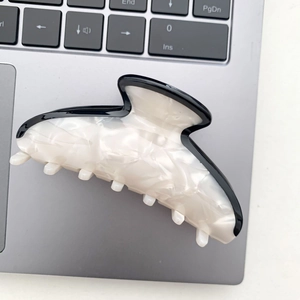 Detail of large acetate hair claw clip with black and white marble pattern on laptop