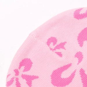 Macro di berretto in maglia rosa con motivi a fiocco e trama di lana dettagliata
