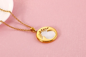 Macro detail of gold round pendant necklace with white shell inlay and hollowed design