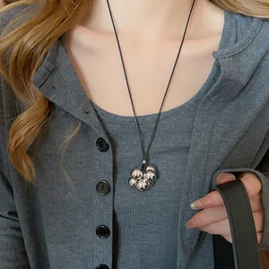 Collana moderna con pendente a bolle d'argento e cordino nero indossata da una modella