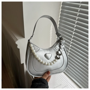 Close-up of silver crescent bag with heart embossing and decorative pearl chain detail