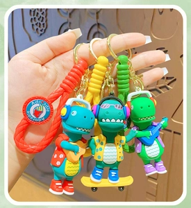 Detail of Adcradle cartoon dinosaur keychains with colorful braided ropes and gold rings