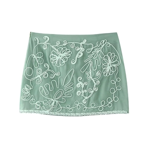 Détail de la jupe courte vert menthe avec broderie florale blanche et bordure en dentelle