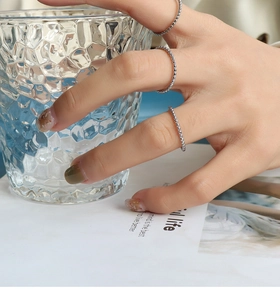 Close-up of three minimalist silver beaded stackable rings worn on a woman's fingers